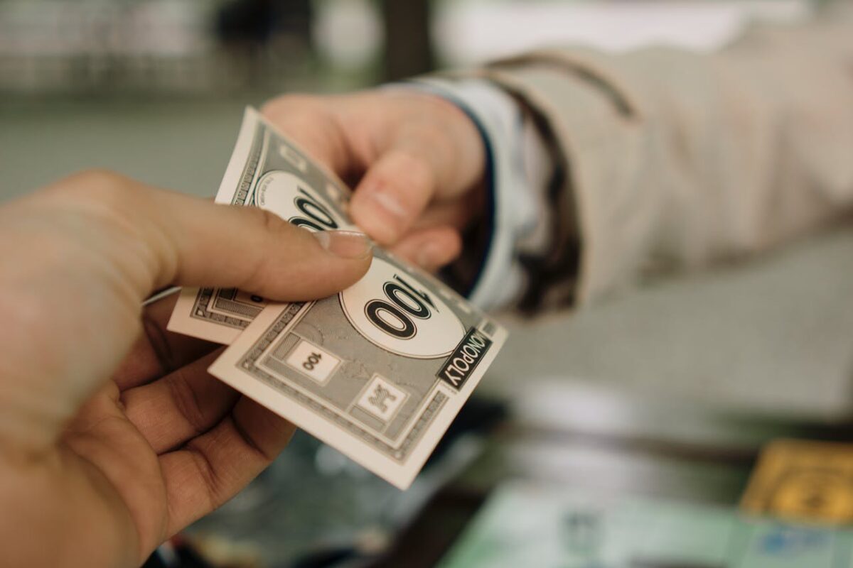 two-hands-exchanging-monopoly-money-bills-
