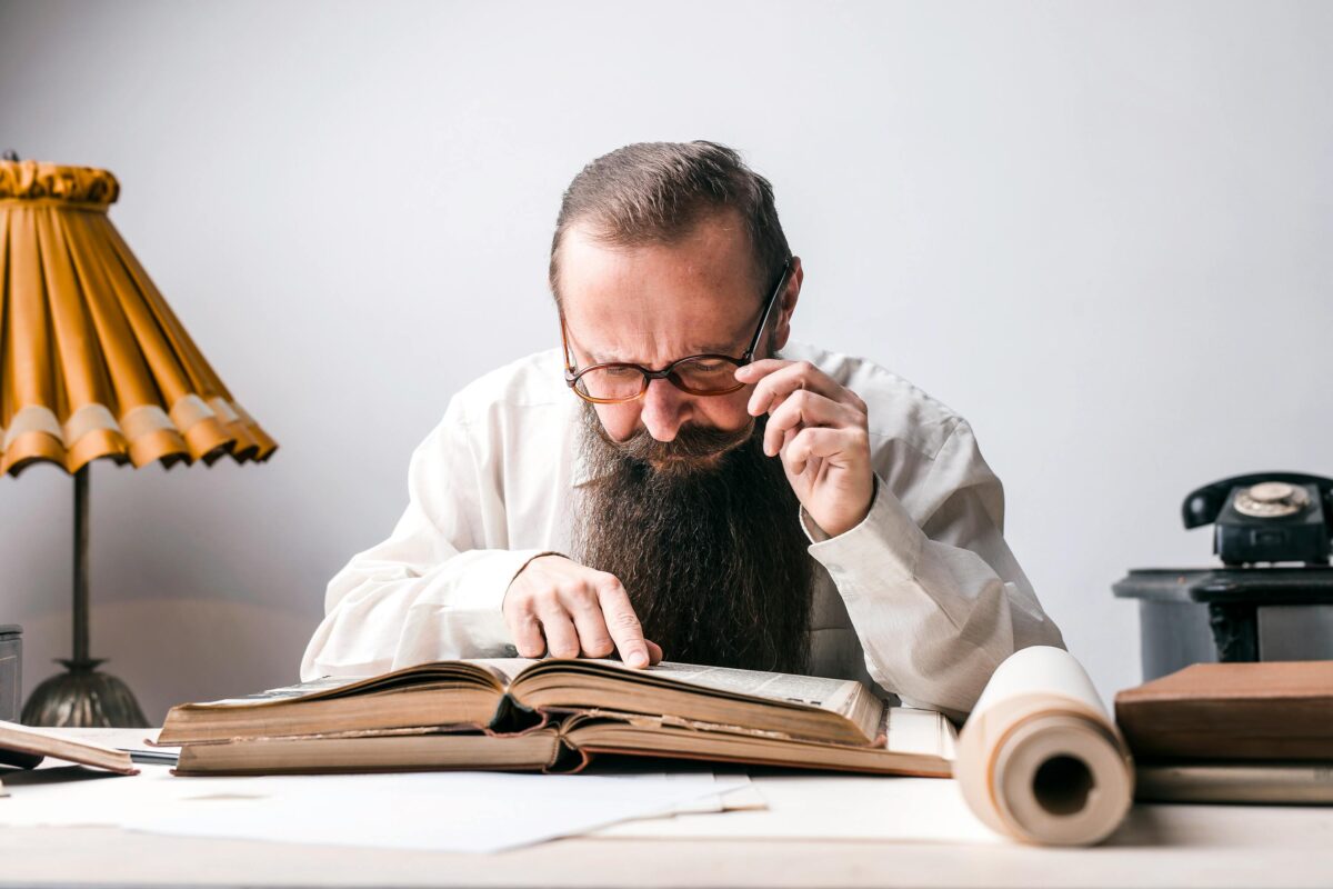 man-wearing-black-framed-eyeglasses-while-reading-book