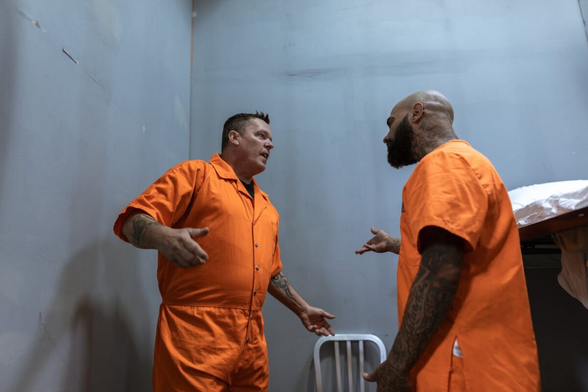 /men-in-orange-clothes-talking-inside-the-room