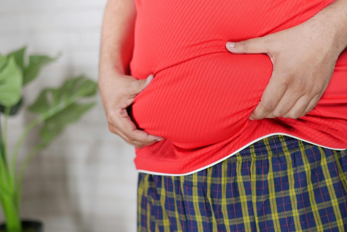 A man in a red shirt holding his midsection, focusing on health issues