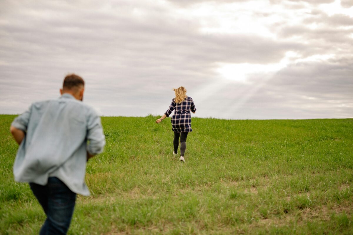 man-and-woman-running-through-a-green-field