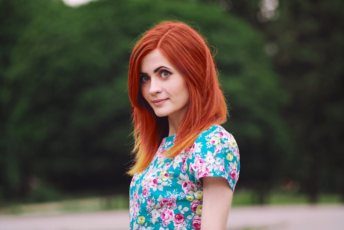 Debunking Redhead Myths: Truths About Gingers You Should Know 1 Portrait of a redheaded woman with a floral top outdoors in Kharkiv, Ukraine.