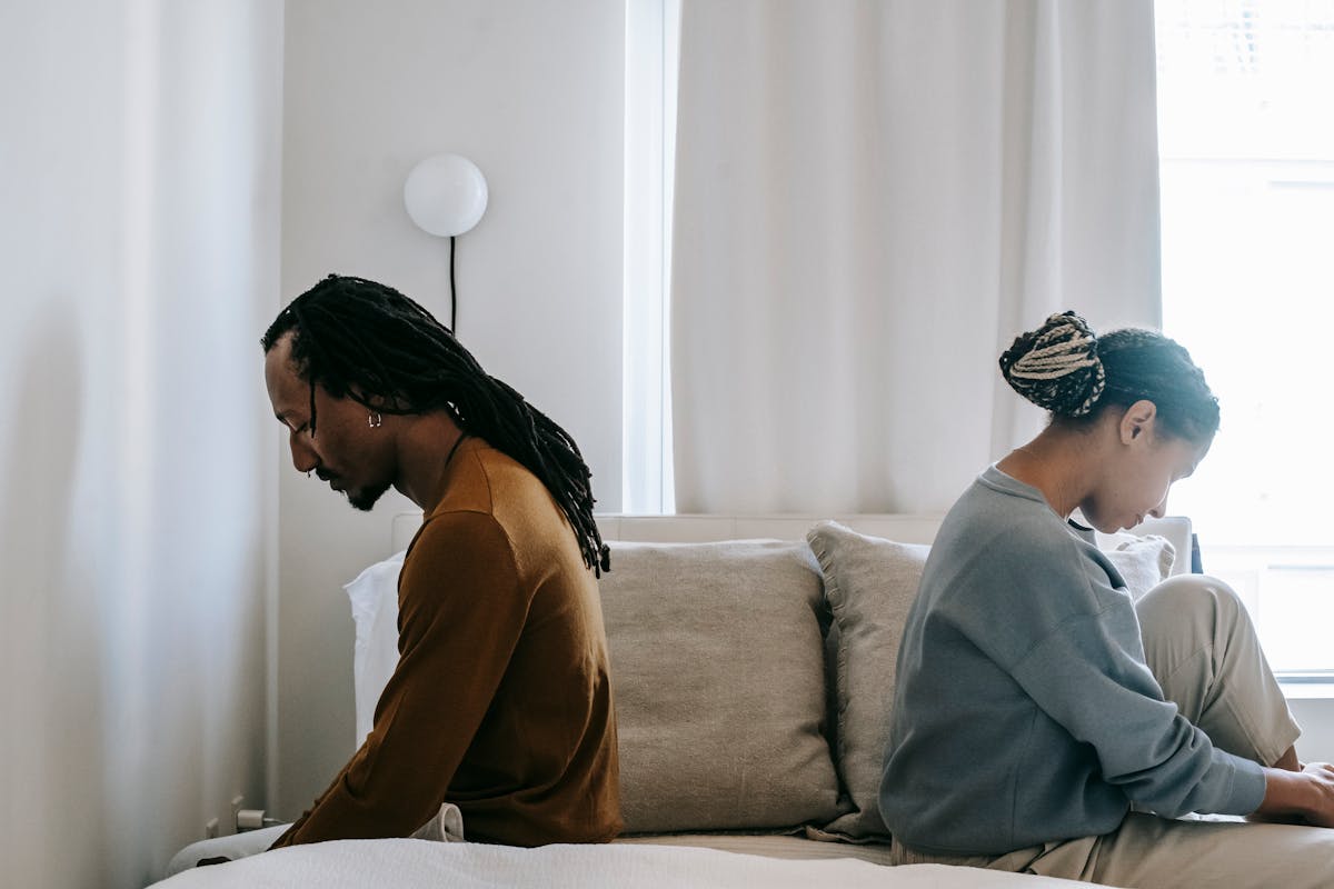 7 Alarming Signs Financial Anxiety is Destroying Your Love Life 2 Side view unhappy sorrowful African American couple sitting on bed back to back after having argument