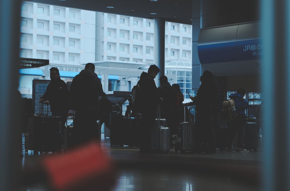 10 Major Travel Struggles and How We Can Make Every Trip Less Stressful 3 Silhouetted travelers wait with luggage in a Japanese railway station, focusing on transportation and travel.