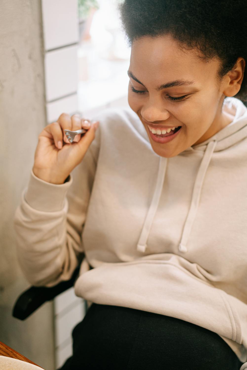 Smiling pregnant woman in a casual setting, enjoying a happy moment indoors.