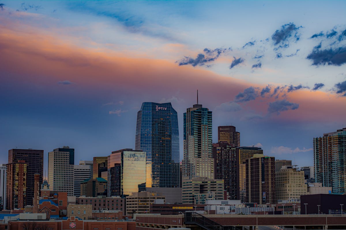Stunning view of Denver's cityscape with skyscrapers under a colorful sunset sky.