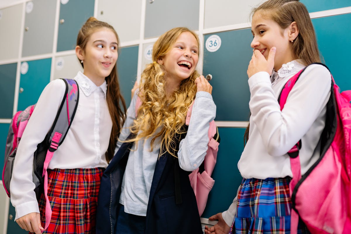 10 Warning Signs Your Friends Are Damaging Your Relationship And How You Can Protect It 3 Three girls in school uniforms laughing and talking by lockers, indoors.