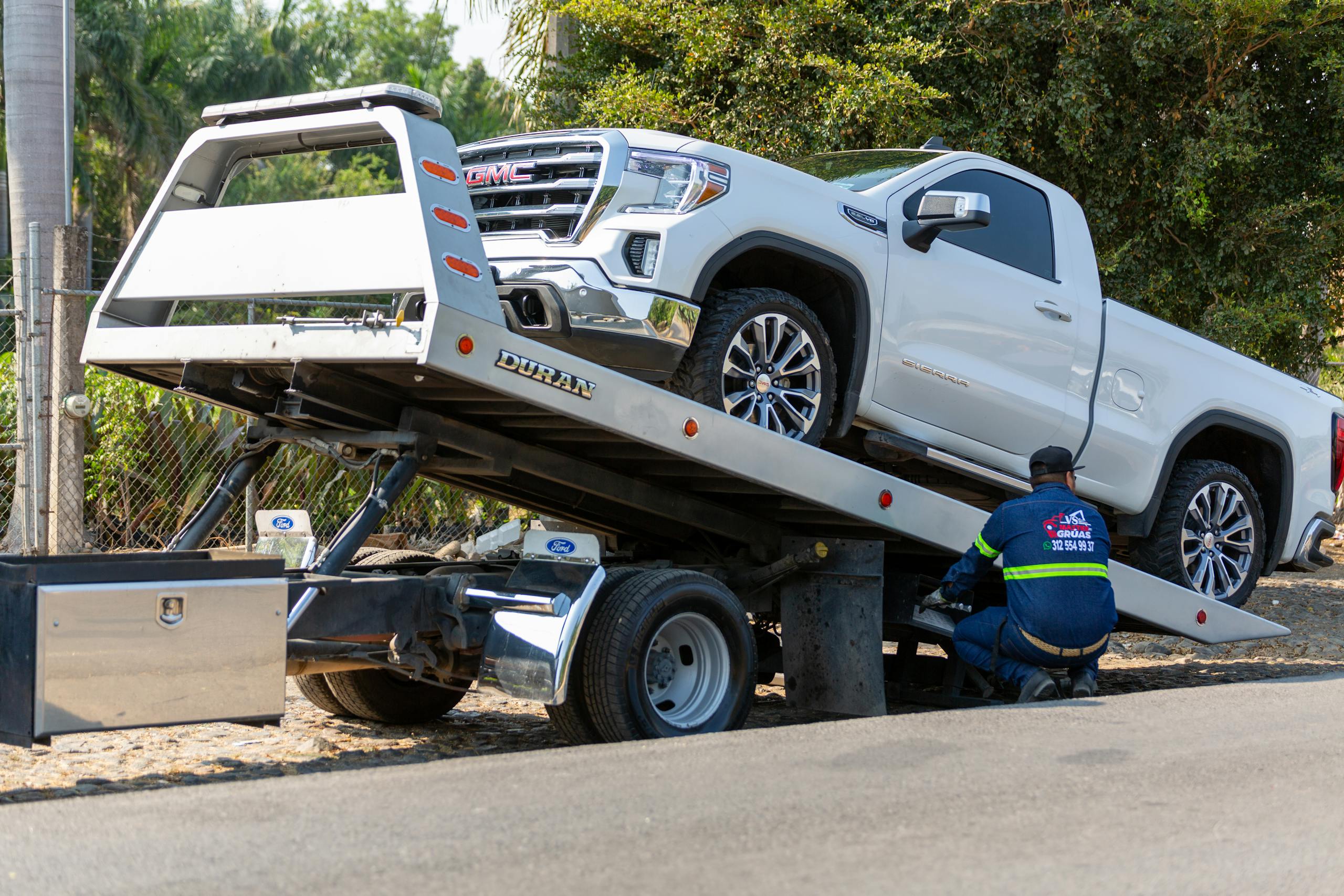8 Disturbing Details About the Omaha Sinkhole That Swallowed Two Cars 2 Tow truck operator loading white GMC pickup truck on street in daytime.