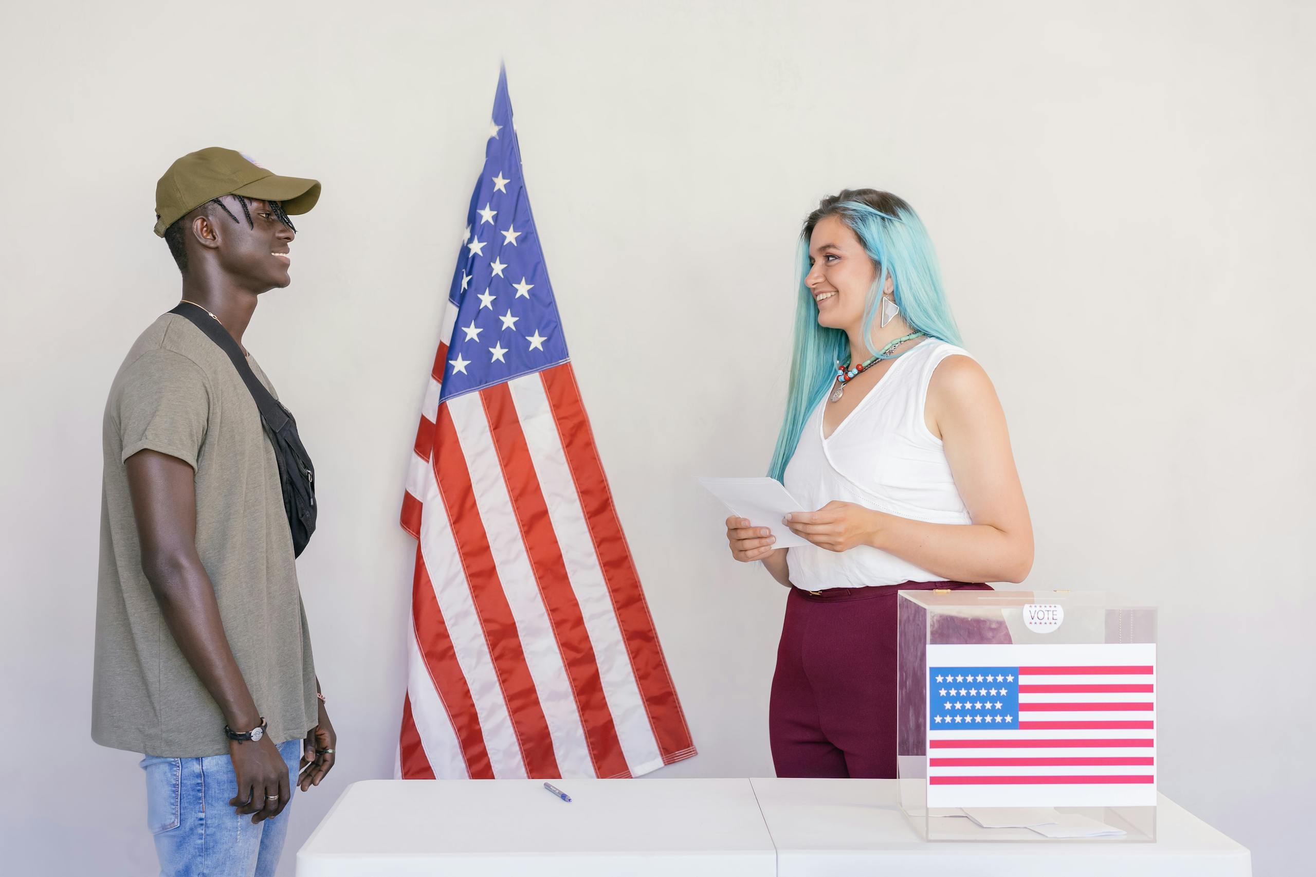 10 Disturbing Reasons Modern Friendships Are Falling Apart in America 3 Two diverse young adults engaging in a voting process next to an American flag.