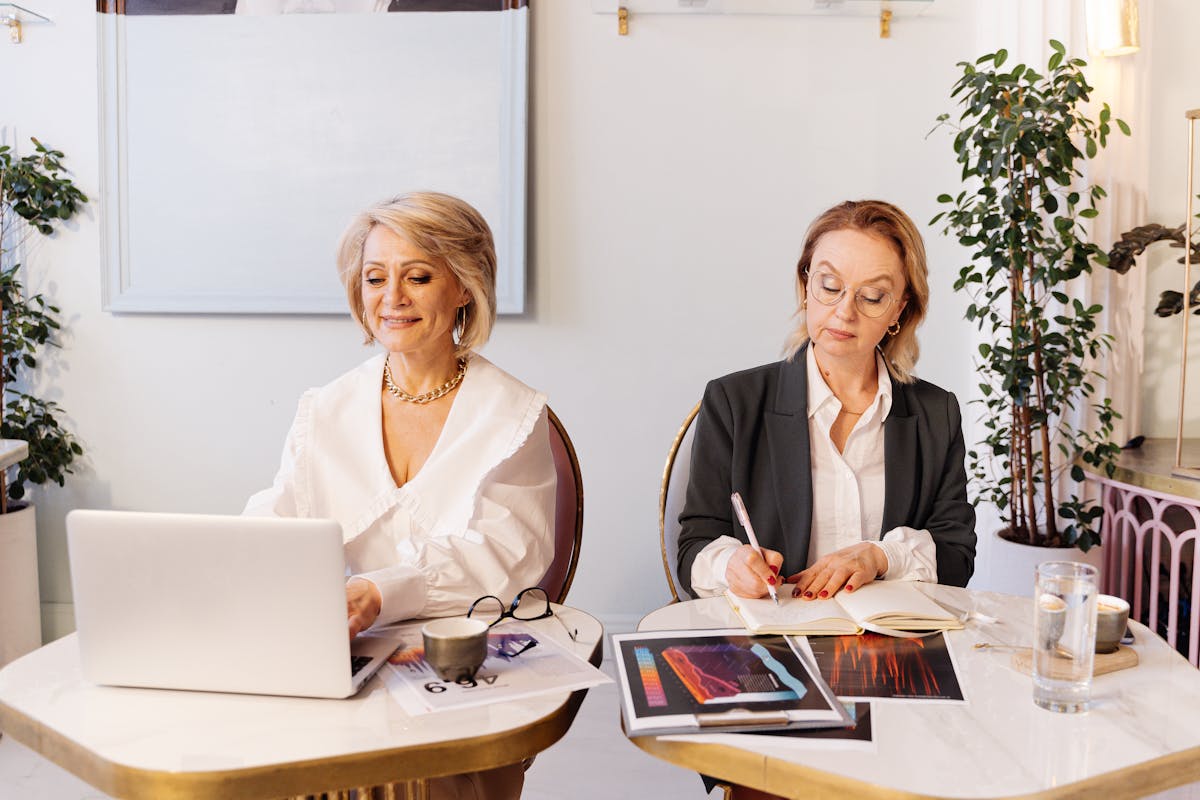 10 Gen X habits bosses believe are career killers 3 Two professional women working together in a modern office, one using a laptop and the other taking notes.