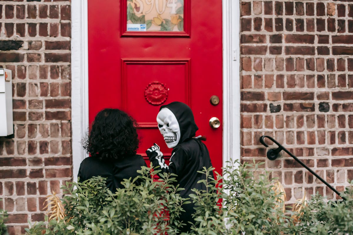 10 Truly Evil People Who Used Halloween as the Perfect Cover 2 Unrecognizable kids wearing black costumes with masks in Halloween while knocking on house door