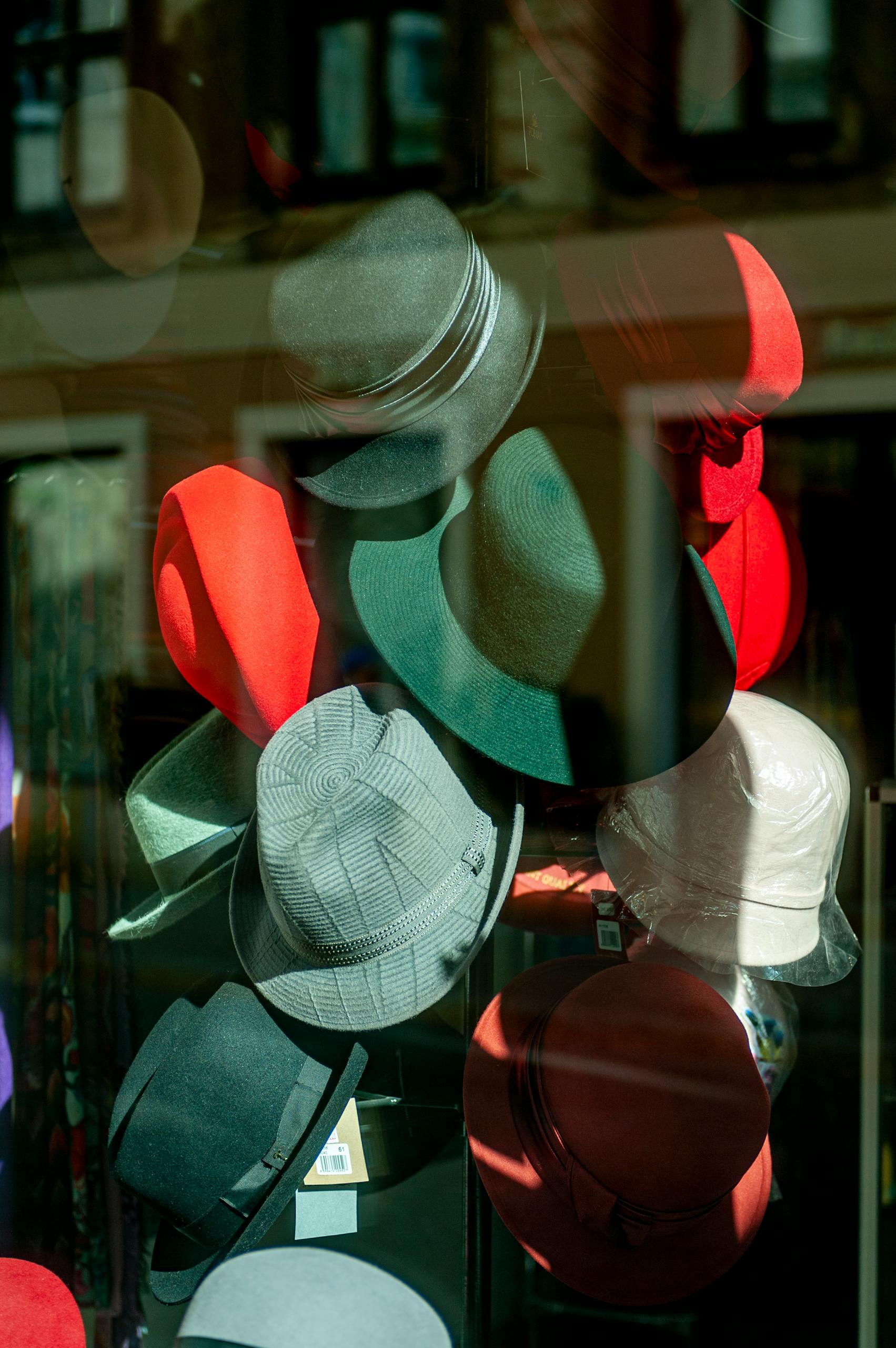 7 Fashion Trends That Were Basically Death Traps 2 Vibrant assortment of hats in a store window in Lviv, Ukraine, reflecting city architecture.