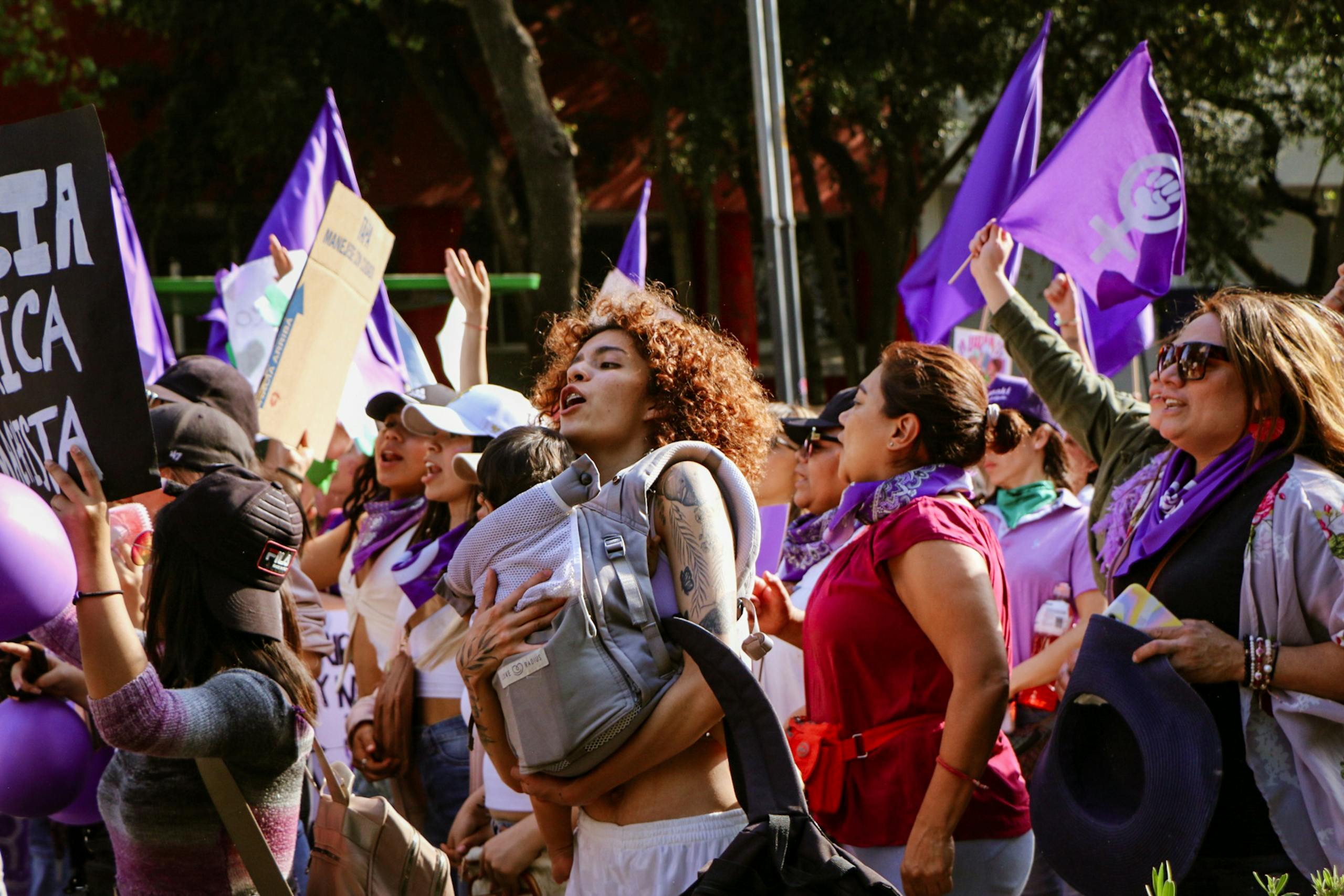 7 Uncomfortable Reasons More Women Are Saying No to Motherhood 4 Vibrant street march showcasing unity and feminism under vibrant purple flags.