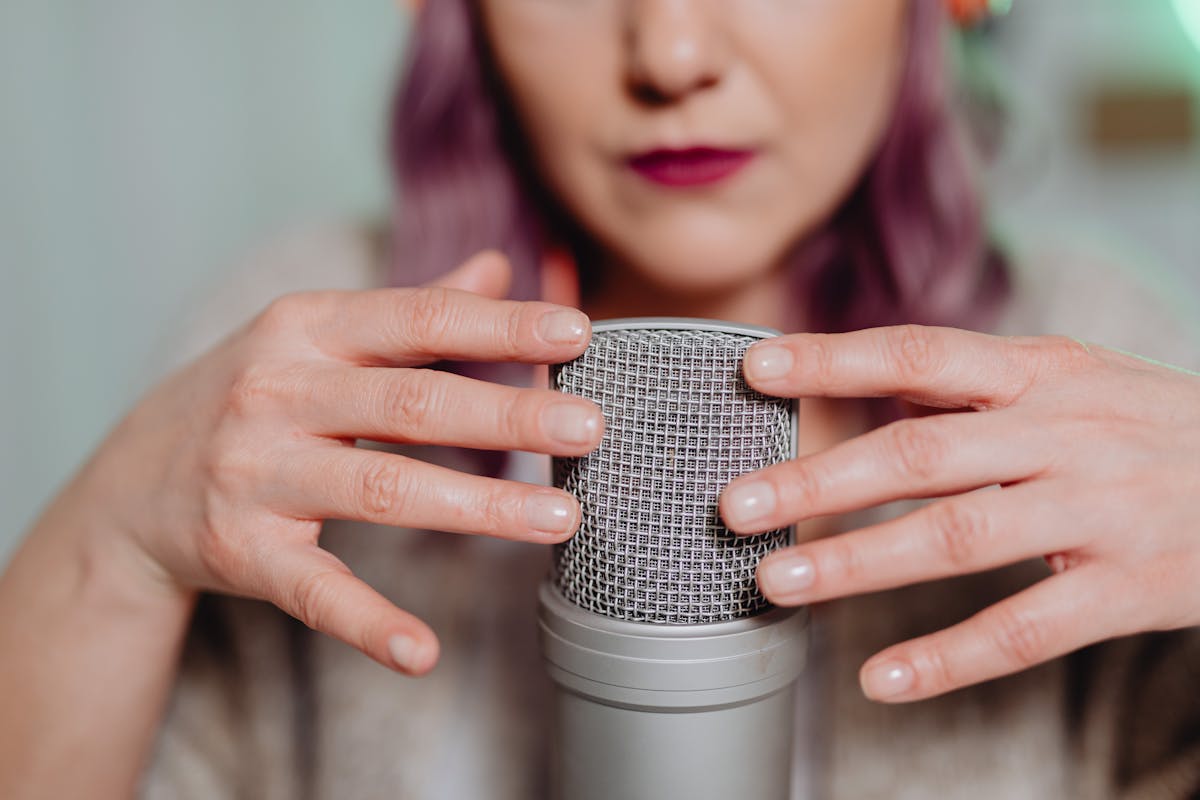 Woman using a microphone for ASMR recording indoors, creating soothing audio.