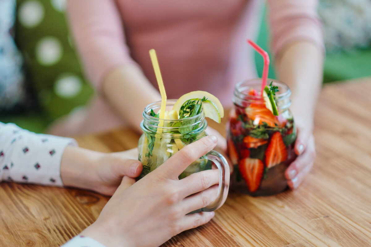 10 Spiritual Trends That Are More Dangerous Than They Seem 2 Close-up of the hands of two girls holding glass jars with red strawberry and yellow lemon lemonade. The concept of summer soft drinks.