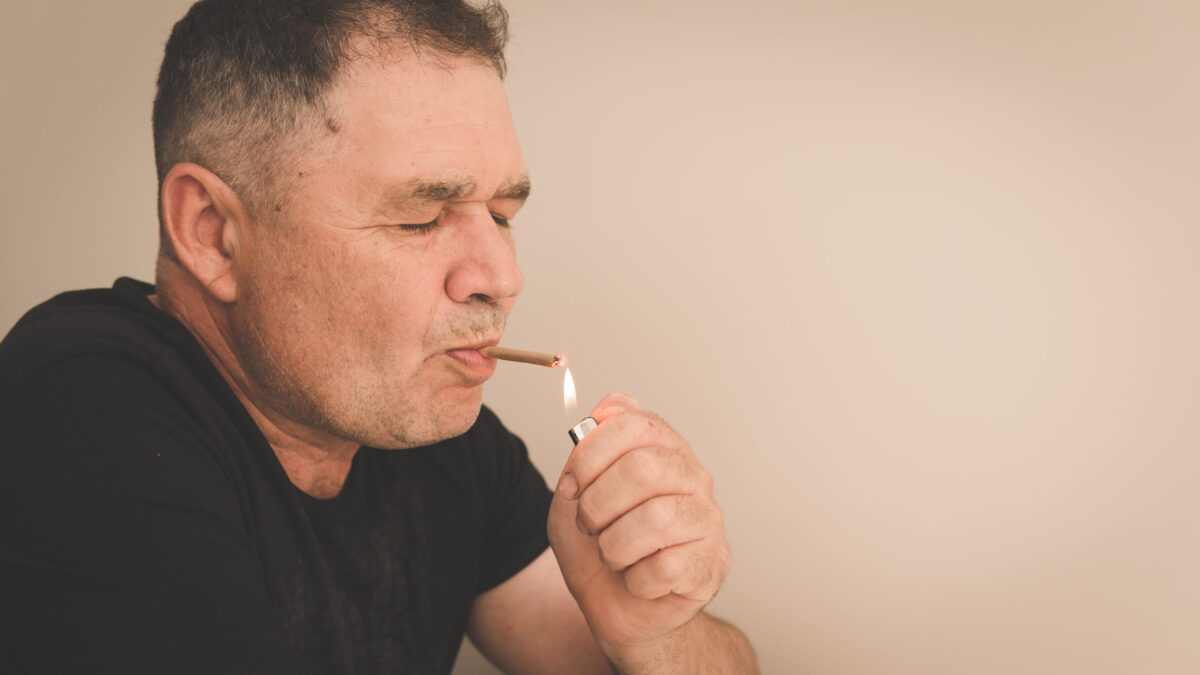 The adult man smoking medical marijuana joint close-up. Smoking cannabis indoors. Cannabis is a concept of herbal medicine