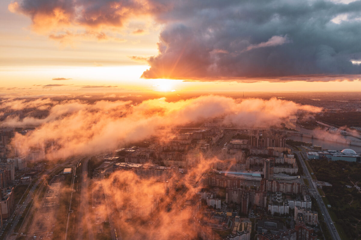 Urban landscape , aerial top view with low flying clouds over a residential area of the city, view of the horizon and the dawn of the sun