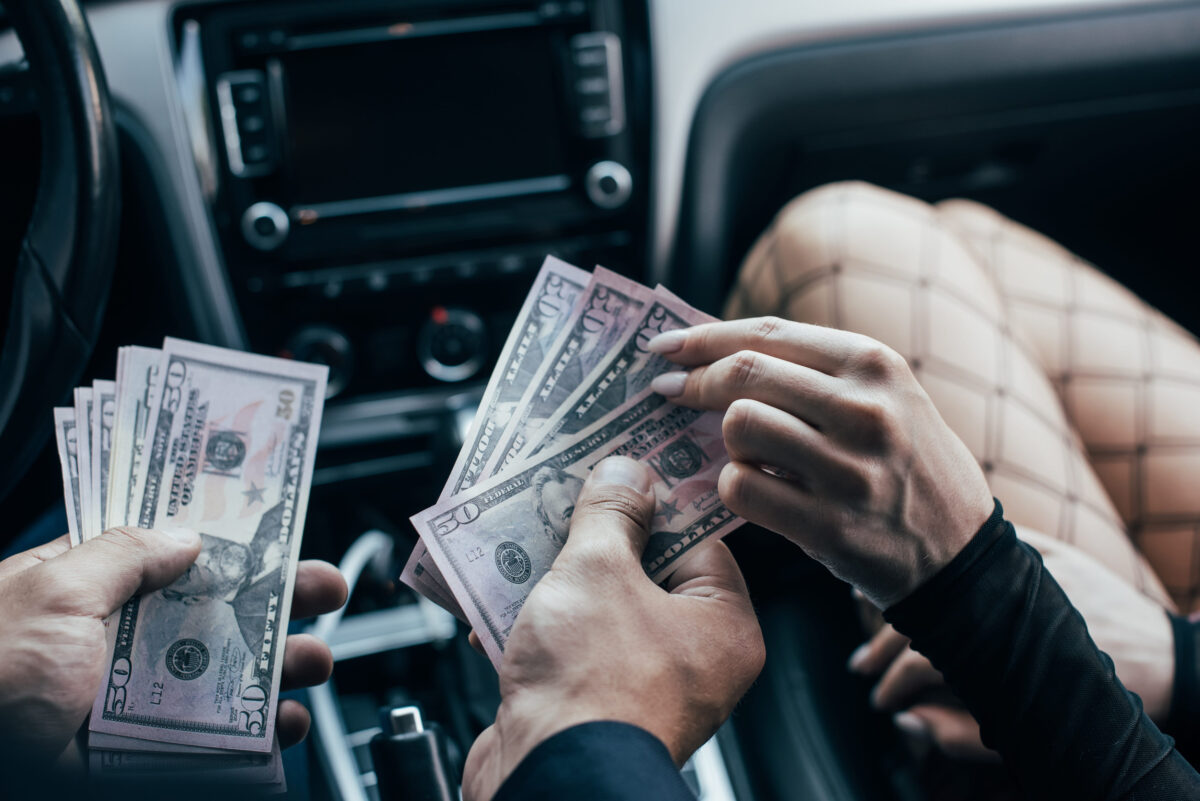 8 Dark Reasons Sex Traffickers Often Avoid Experienced Sex Workers as First Targets 2 cropped view of client paying dollar banknotes to woman in car