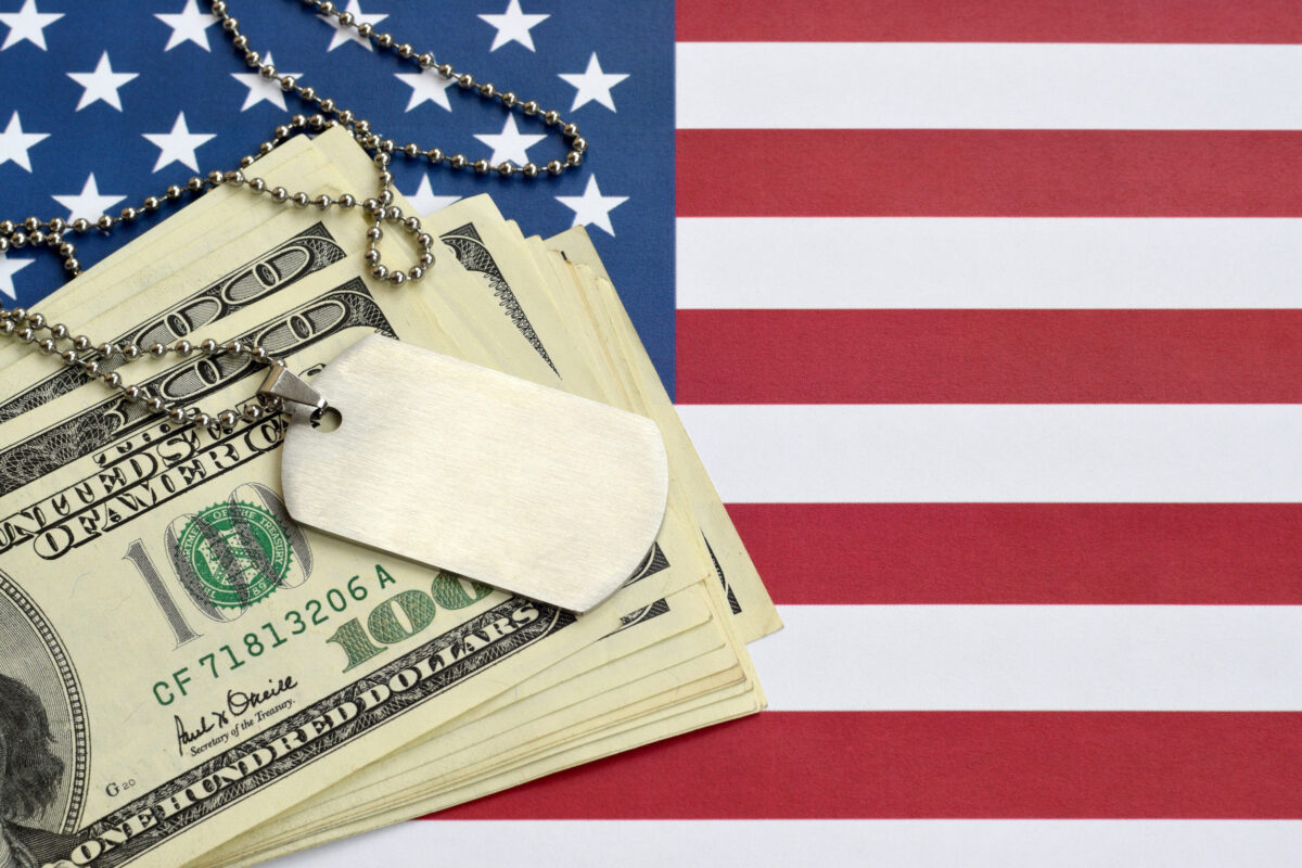 Army identification medallions and dollar bills on United states flag. Military pension, salary in the army or military insurance, contractors recruits and mercenaries