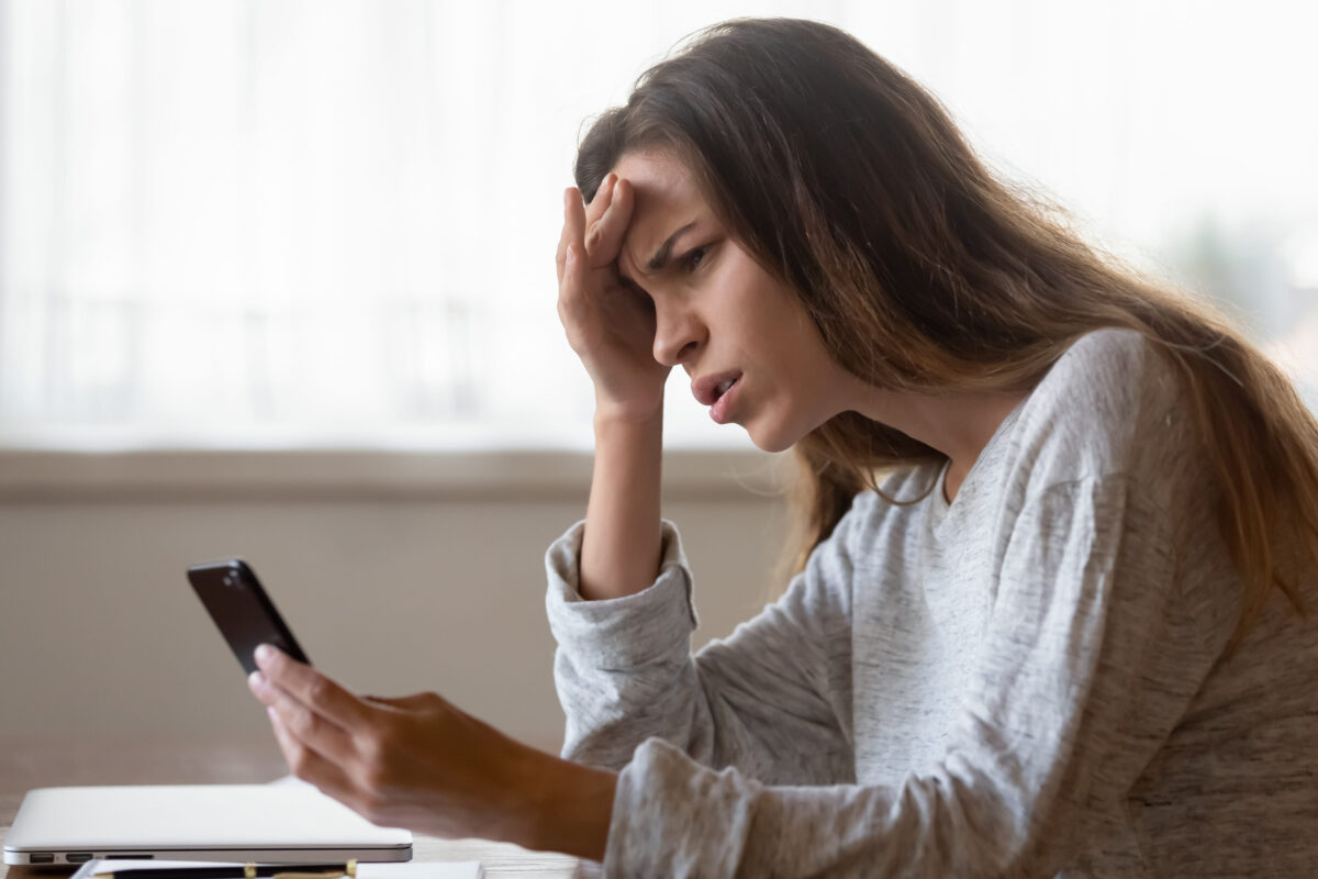 Pensive mad young woman look at smartphone screen having slow internet connection on gadget, thoughtful angry millennial girl experience cellphone operation problems, spam message on cell