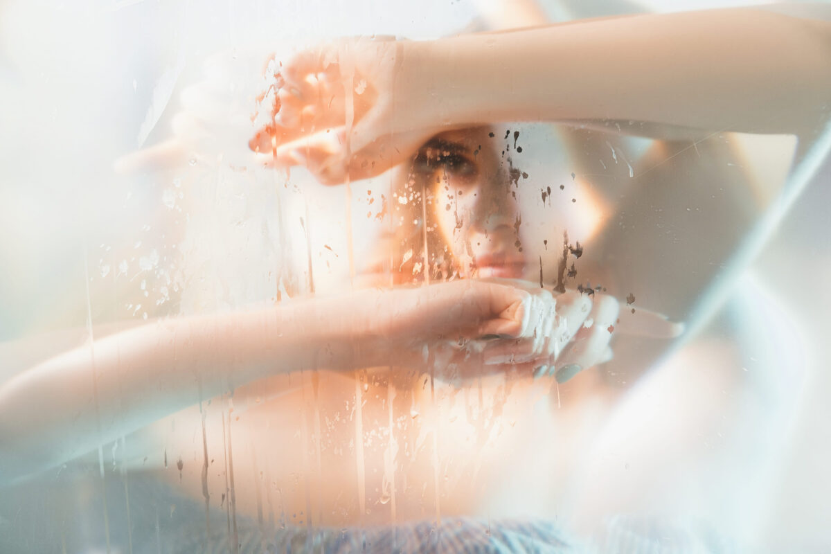 Art portrait. Feminine beauty. Double exposure blur sensual pensive woman silhouette with stained steamed glass holographic iridescent glow effect. Skincare wellness. Melancholy dream.