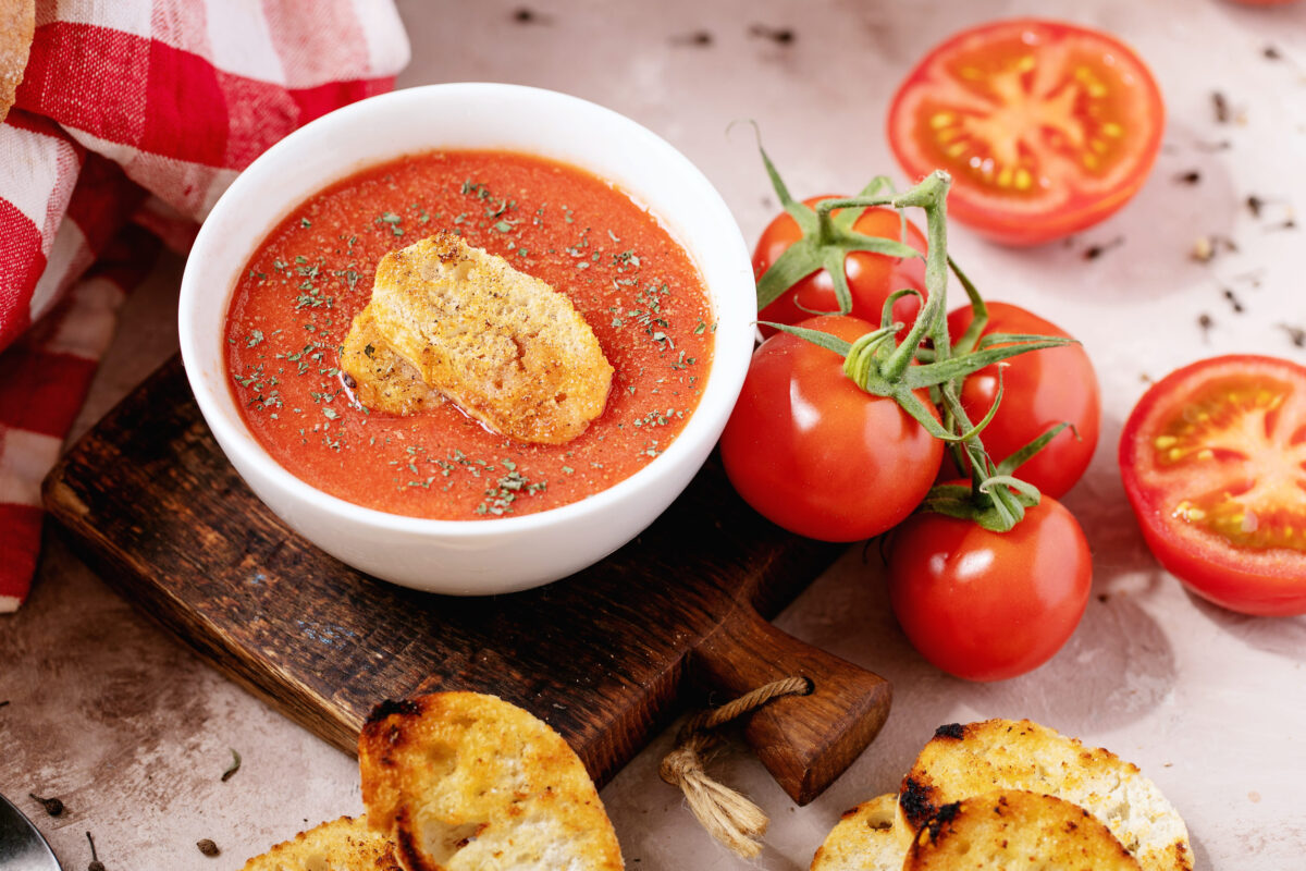 10 Cheap Meals Americans Crave Most When They’re Financially Burned Out 2 Homemade tomato soup served with fresh bio tomatoes and bread over white texture background. Top view, flat lay. Copy space