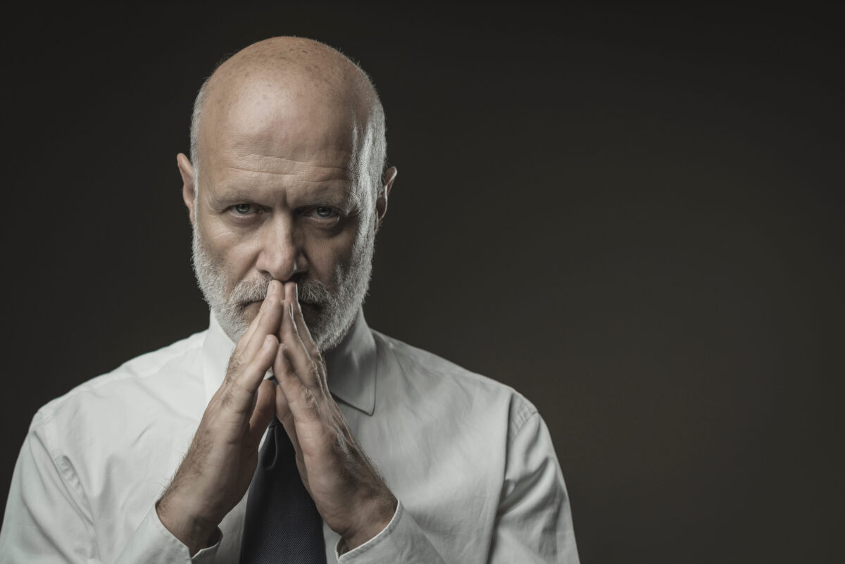 Confident senior corporate businessman staring at camera and posing, leadership and individuality concept