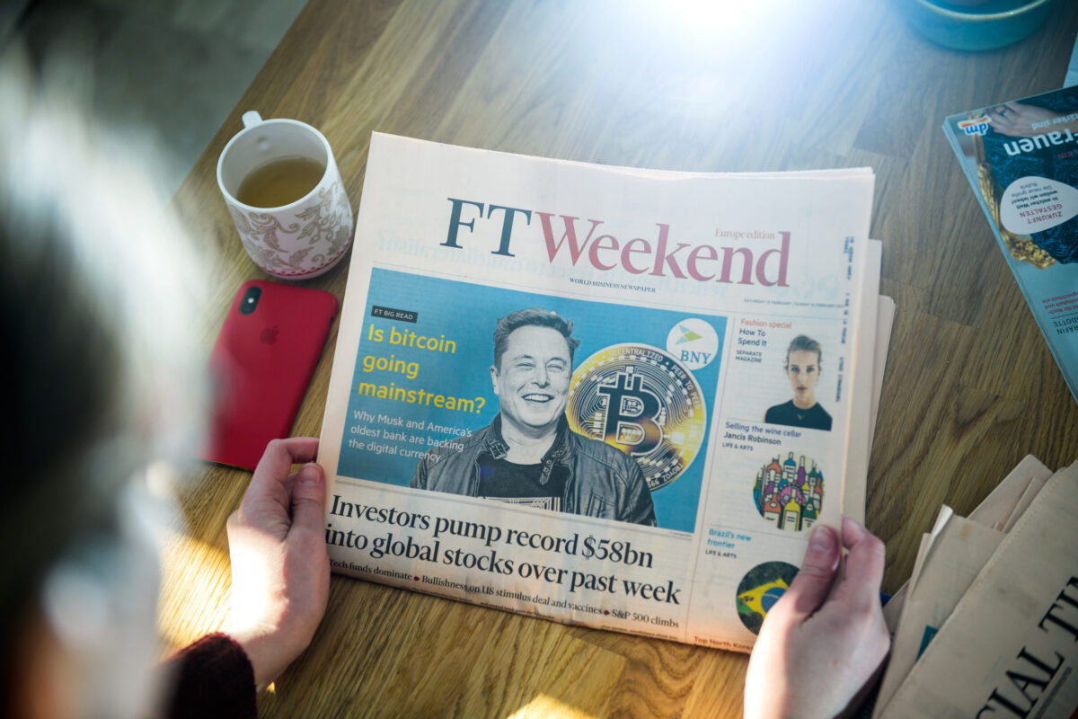 Elon Musk’s Trillion-Dollar Moment Turns SpaceX Into Wall Street’s New Obsession 4 Paris, France - FEb 13, 2021: POV business woman reading Financial Times newspaper on kitchen counter with Elon Musk headline smiling and text Is bitcoin going mainstream