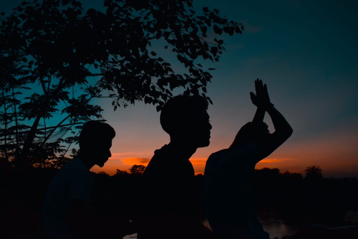 Silhouette of three young guys in front of beautiful sunset evening