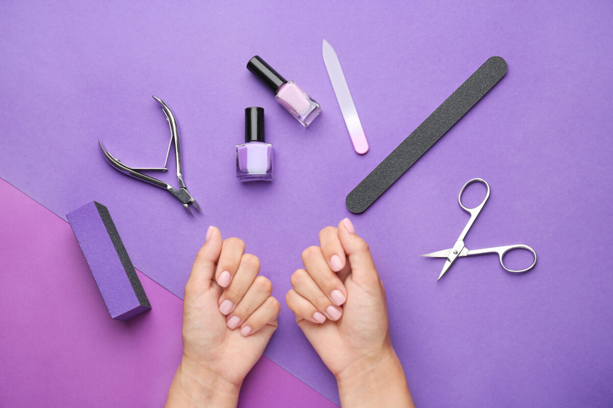 Female hands with supplies for manicure on color background