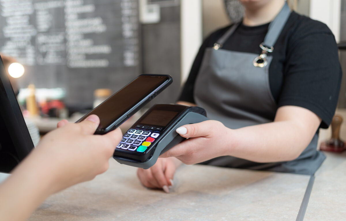 10 Ways America’s SNAP Shakeup Is Hitting Families Far Beyond the Grocery Aisle 3 A woman pays with a phone with NFS technology on the phone with a contactless terminal in a cafe shop or cafeteria. Mobile phone for order payment with nfs technology.