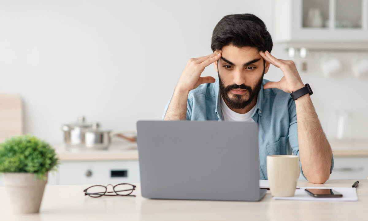 10 Ways the Obamacare Coverage Drop Became America’s New Health Care Warning Sign 2 Portrait of stressed pensive arab man sitting at desk with laptop in kitchen, depressed freelancer touching temples, free space