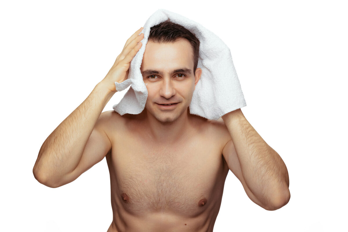 Portrait of young man after shower, drying hair with towel after washing isolated over white background