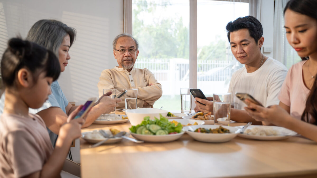 Parents Are on Devices During Meals Even More Than Their Kids, and The Family Dinner Table is Paying The Price 1 Asian Addicted family use mobile phone while eating breakfast on table. Upset Elderly grandfather feel unhappy angry and troubled from ignorance son and daughter to not pay attention to senior old man