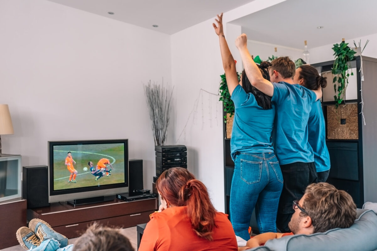 friends jumping for joy after their teams victory, watching football match on TV. opposing team sad after defeat