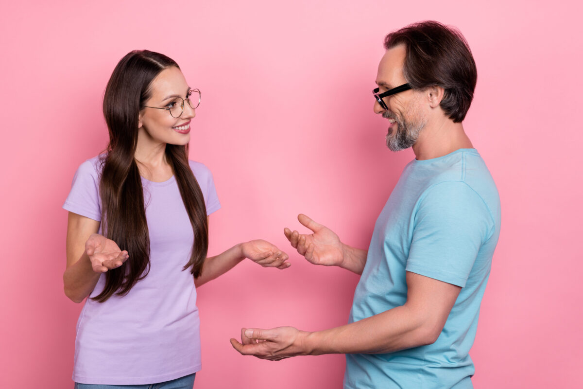 Photo of two cheerful positive partners communicate discuss chatting isolated on pink color background