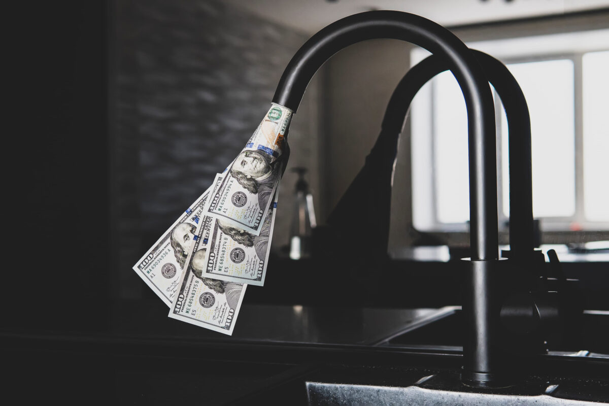 The Woodlands May Face Higher Water Bills as Aging Infrastructure Demands Attention 2 Tap with dollars flowing out of it. Expensive water supply. The concept of increasing the price of public utilities for the population. Expensive hot and cold water at home.