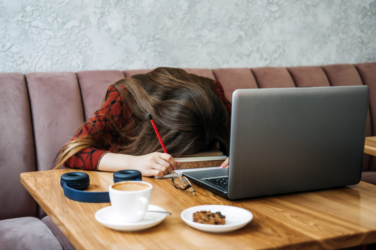 Student girl studying hard exam and sleeping on books in cafe. Tired Girl working