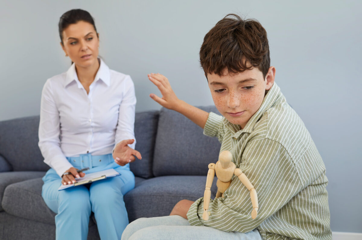 Child having difficulty with communication at therapy session in therapists or psychologists office. Upset, unsociable boy refuses help and wont talk to specialist. Mental health problems concept