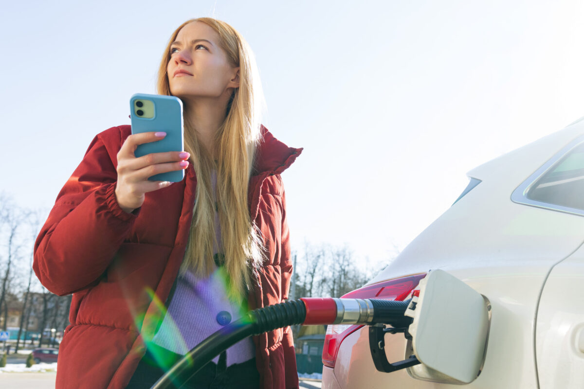 Oil Prices Fall After President Trump’s Iran Deal, But Drivers May Not Be Safe Yet 3 The woman refuels the car and types on her phone. Refueling the car before the trip.