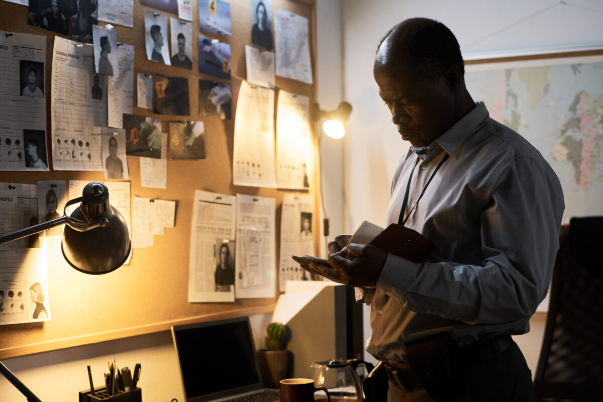 Colorado Mother’s Murder Case Sparks New Law on Digital Response Times 3 Middle-aged African American man attentively examining notes on bulletin board under soft lamp light, surrounded by office supplies in a room with subdued lighting