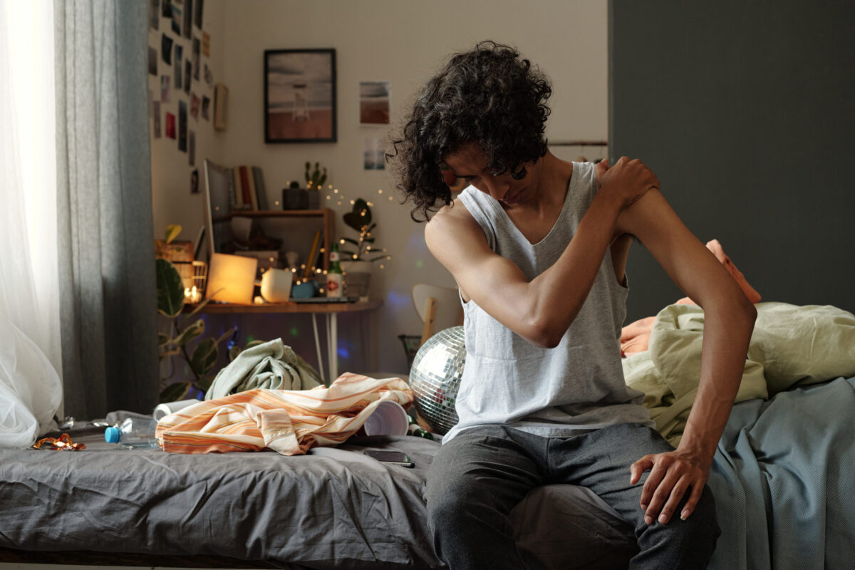 10 Gross Habits Some Men Ignore Like Nobody Notices 4 Young man with headache and other symptoms of hangover sitting on bed and touching shoulder after booze in the morning