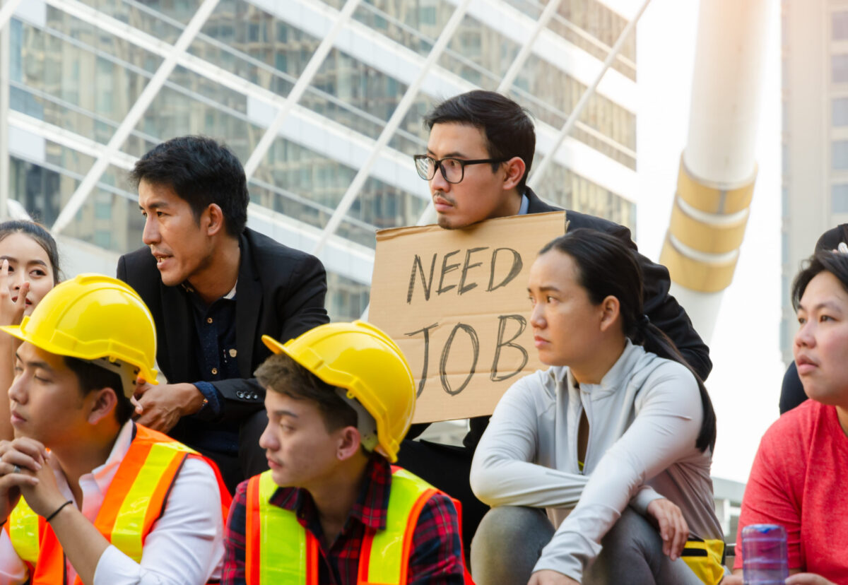 Group of people. A man in black suit holding a sign of NEED JOB,