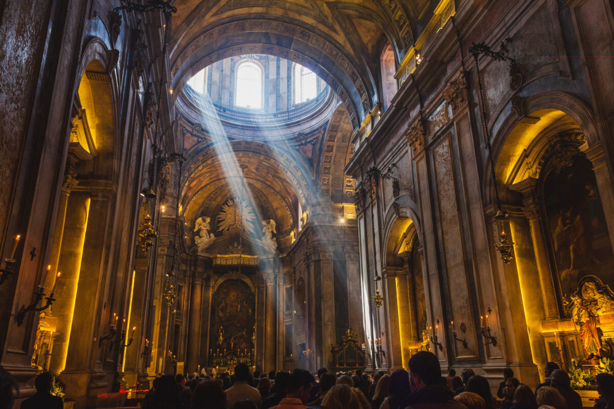 American Churches Face a Brutal Truth as Millions Drift Away From Organized Religion 3 This striking interior photograph captures a grand, ornate church or cathedral, bathed in soft light. Sunbeams filter through a large circular window in the dome, casting divine light that highlights the detailed architecture.