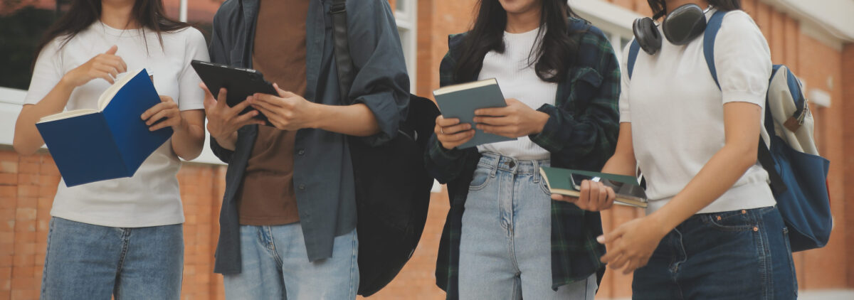 Happy students walking together on university campus, chatting and laughing outdoors after classes