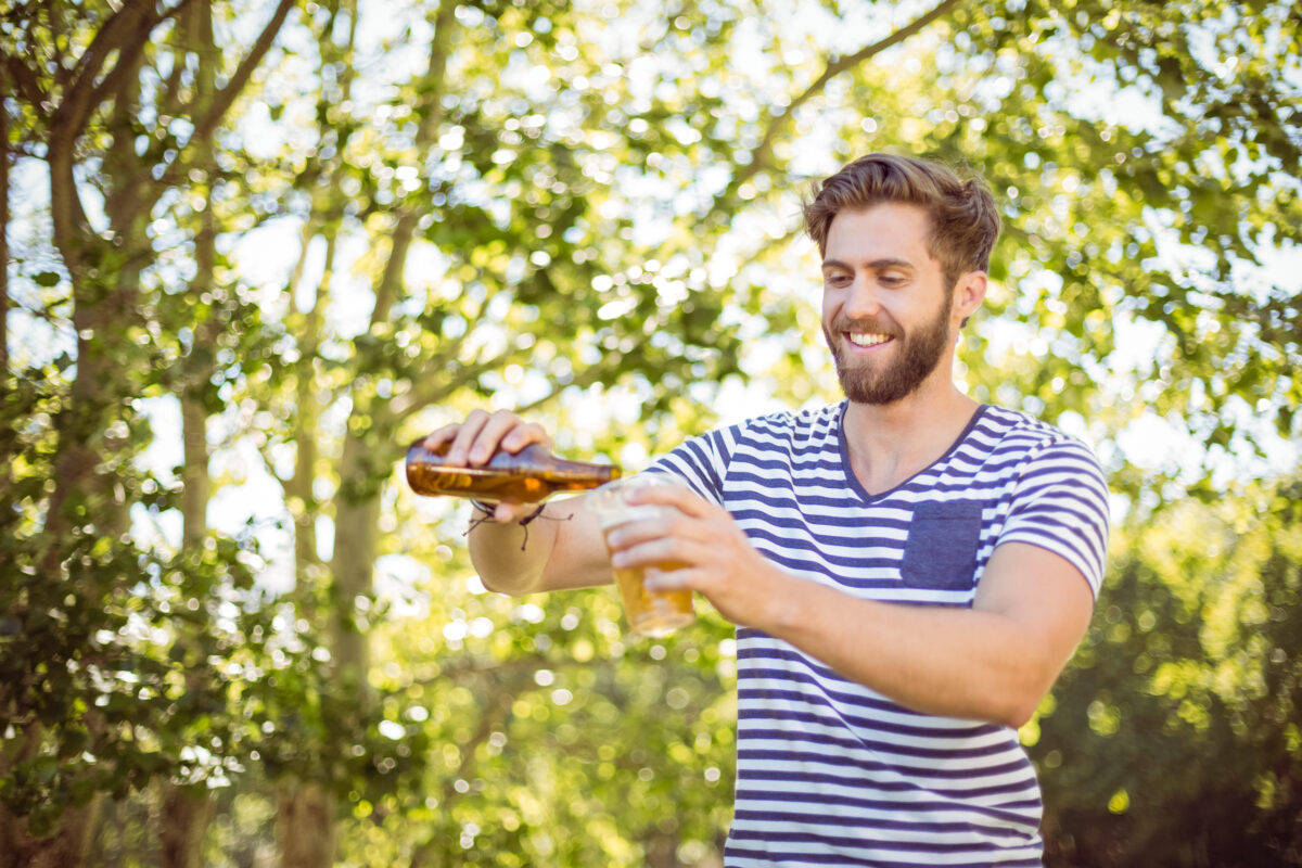 Hipster pouring himself a beer on a summers day