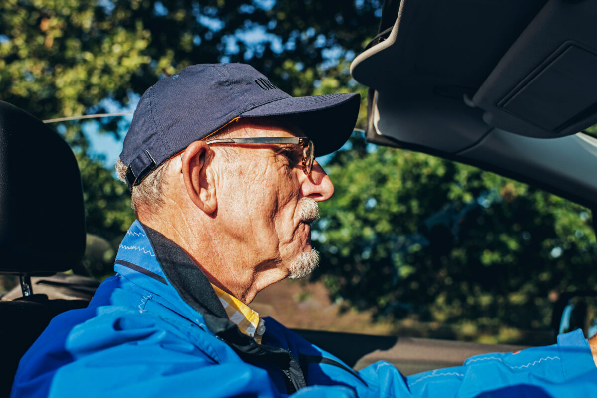 Interior shot of retired man driving convertible car in summer.