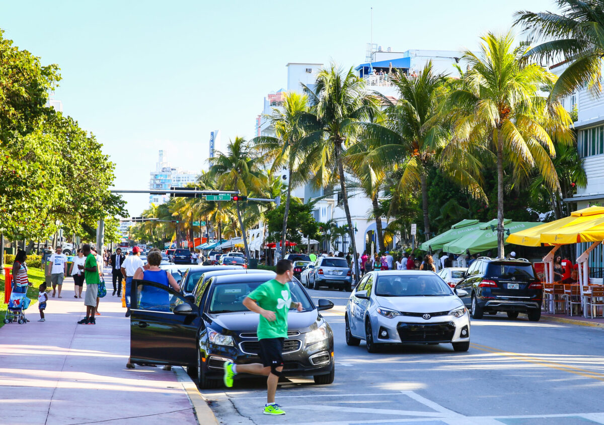 8 Worst States If You Want To Take Vacations More Often in 2026 4 Cars driving and parking in Miami Beach on Ocean Drive, people walking by or running.