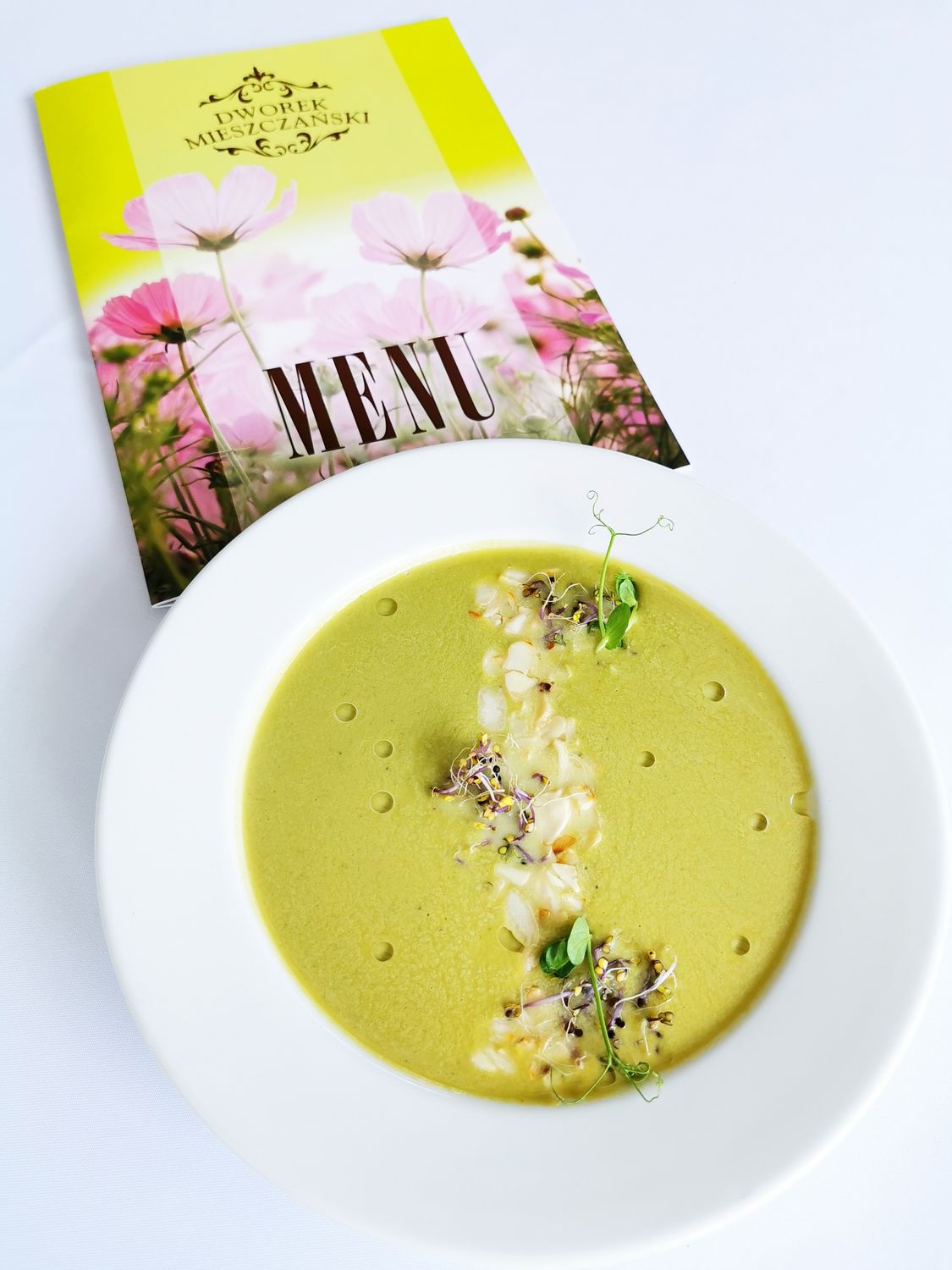 From Kitchen Idea to Thriving Brand: The Real Playbook for Starting a Food Business 2 A bowl of gourmet pea soup garnished with sprouts and served beside a floral menu.