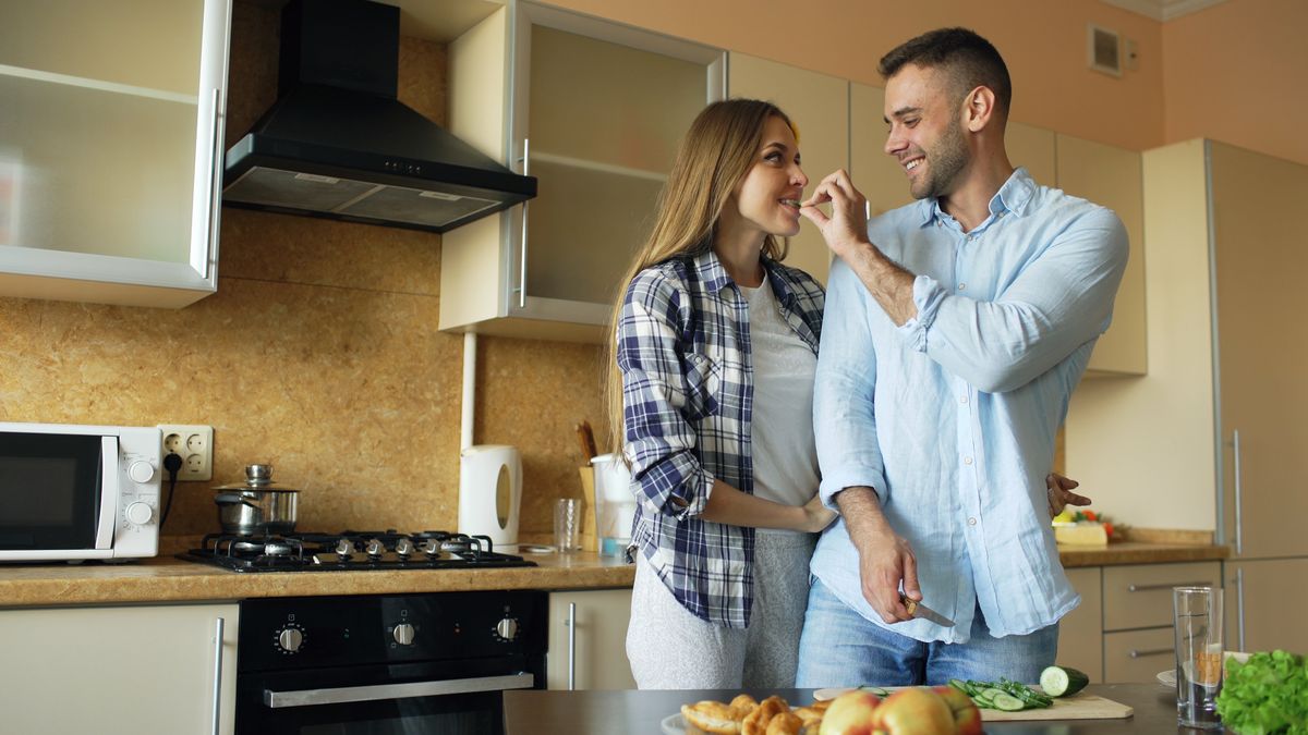 A cheerful couple enjoys cooking together, sharing a fun moment in their modern kitchen.